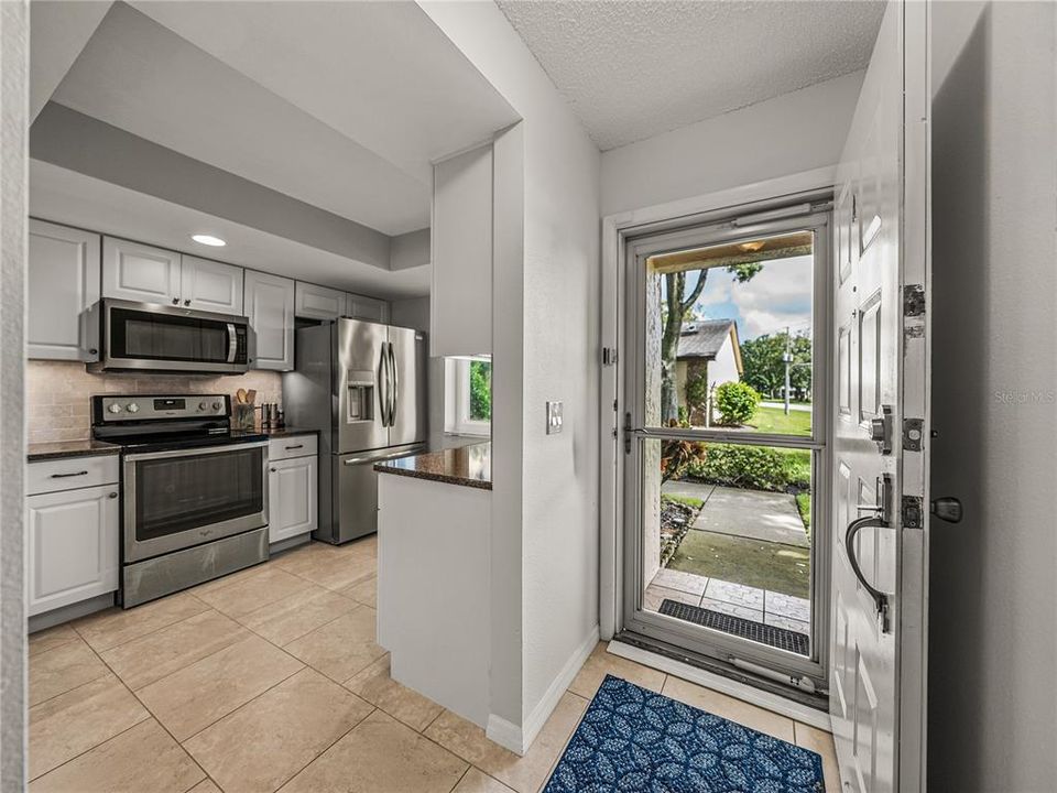 Foyer entrance through newer storm impact glass door and open to updated kitchen~