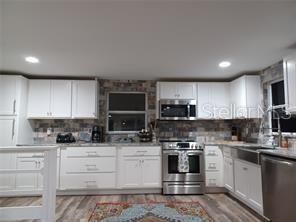 kitchen with granite countertop and matched tile back splash and all stainless steel appliances