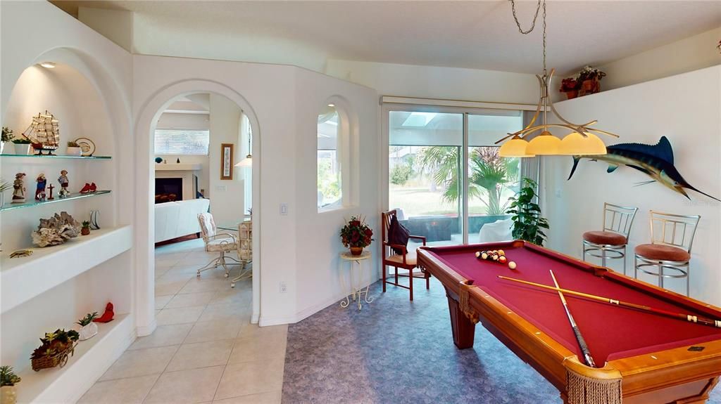 Spacious front room overlooking the lanai and freshwater canal, currently used as a pool game room by the owner, a pool enthusiast. The pool table highlights the generous scale of the room, which can easily be converted into an inviting living space if desired.