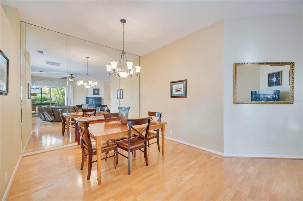 Formal dining room with mirror accent wall and hardwood flooring. Can fit 4-6 person table