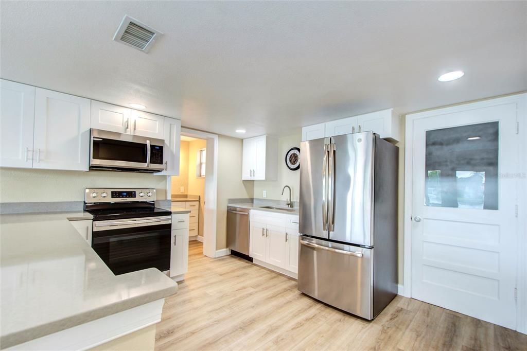 Open kitchen concept with shaker style cabinets, quartz counter tops, and newer stainless steel appliances.