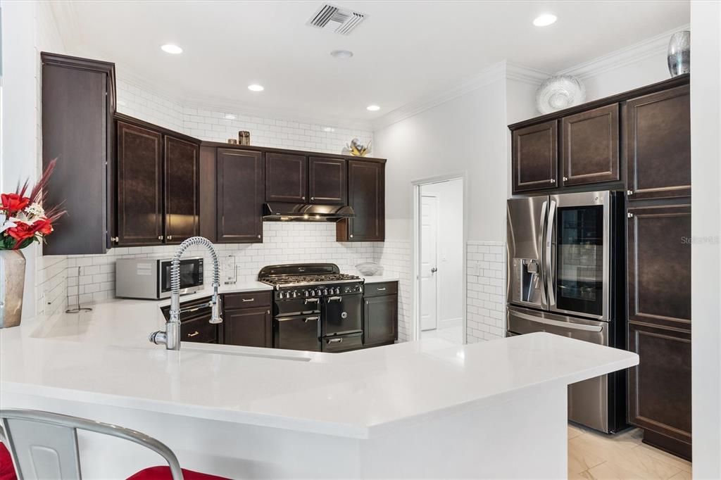 BRIGHT KITCHEN WITH SUBWAY TILES ABOVE AND BELOW CABINETS. QUARTZ COUNTERTOPS.