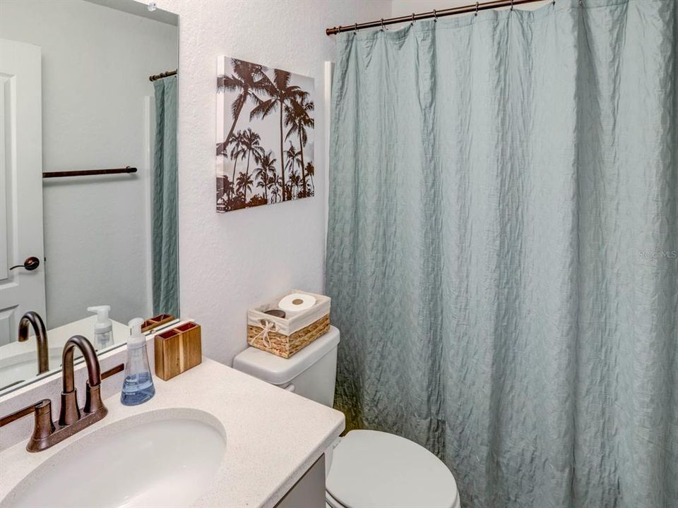 Hall bath with quartz countertops. Tile floors