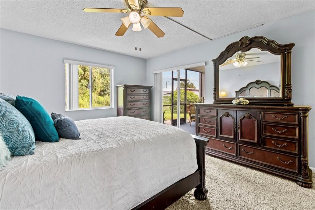 Bedroom has sliders to screened lanai overlooking lovely greenery.