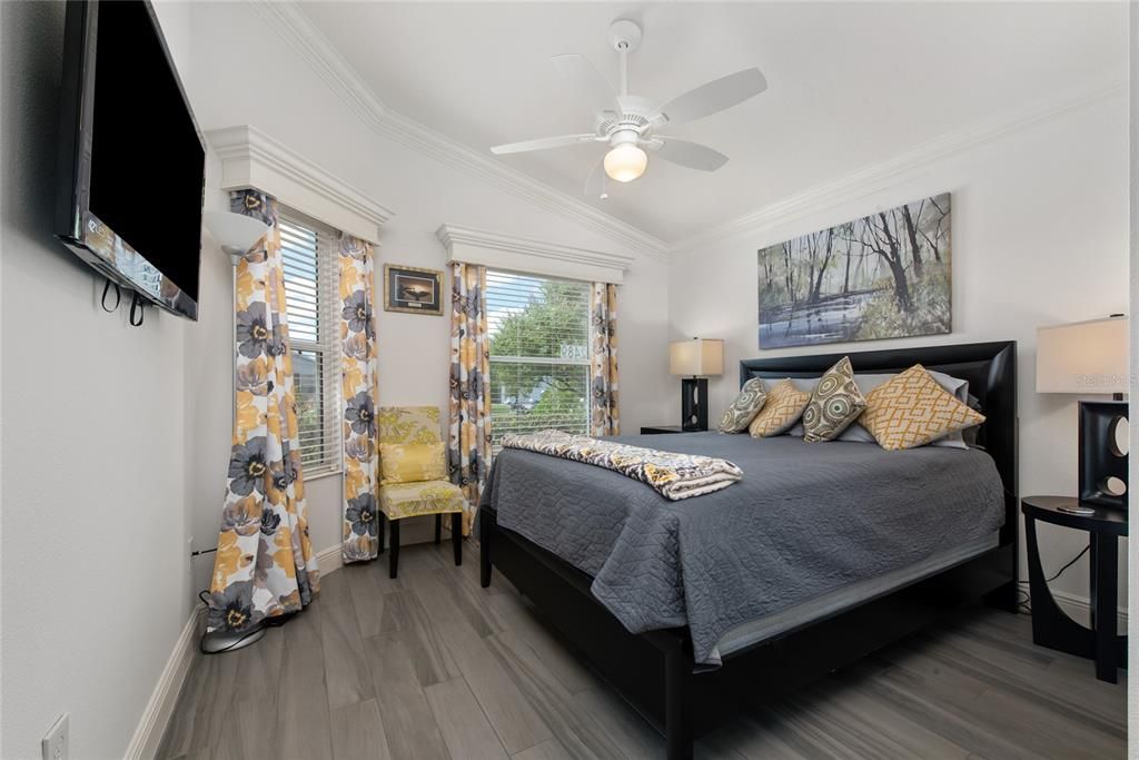 Bedroom 2 - perfect for guests on front of home with king bed, wall-mounted 48" TV, lighted ceiling fan, and window finishings.