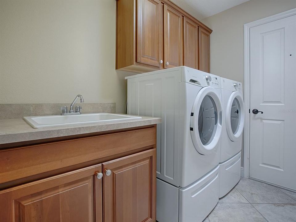 LAUNDRY ROOM WITH FRONT LOAD WASHER AND DRYER ON PEDESTALS (THEY DO CONVEY WITH THE HOME) EXTRA CABINETS AND BUILT-IN SINK.  THIS DOOR LEADS TO THE GARAGE.