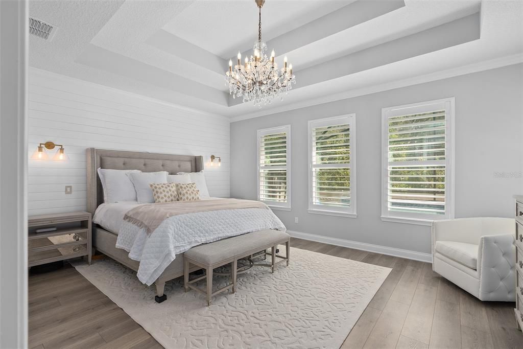 Primary bedroom with tray ceiling and white shiplap accent wall