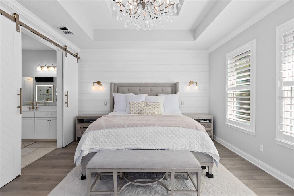 Primary bedroom with tray ceiling and white shiplap accent wall