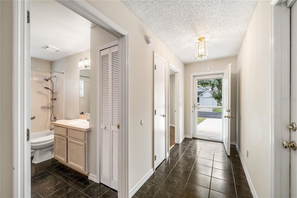 Tiled foyer with line-of-sight to the screened lanai /  Florida Room.  Spacious Guest bath is at the left