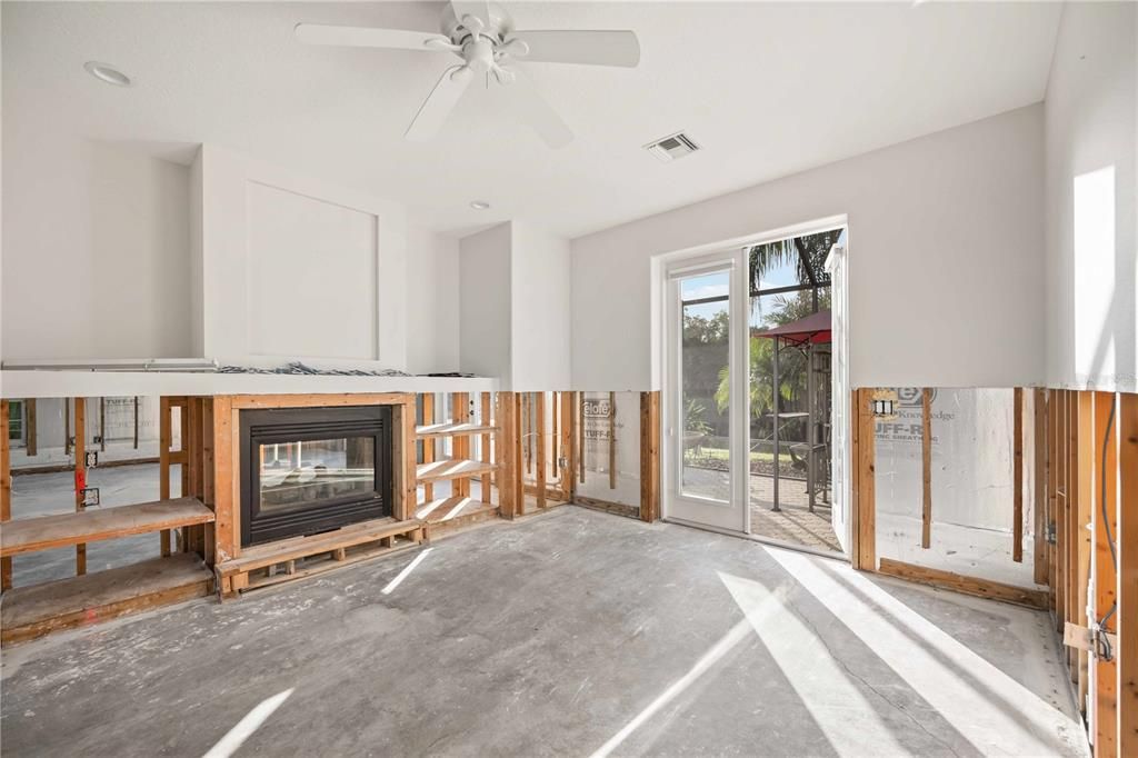 Owner's bedroom (primary bedroom) with french doors leading to paved back porch, and electric fireplace.