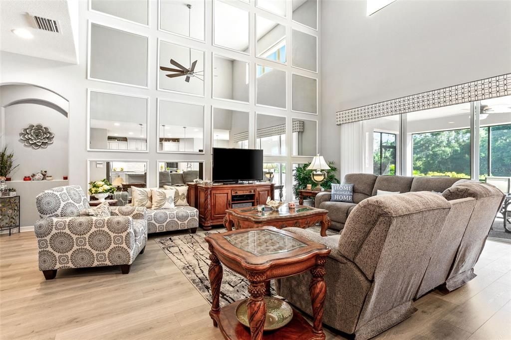 The living room has a two story mirrored feature wall reflecting the natural light pouring in from the sliders.