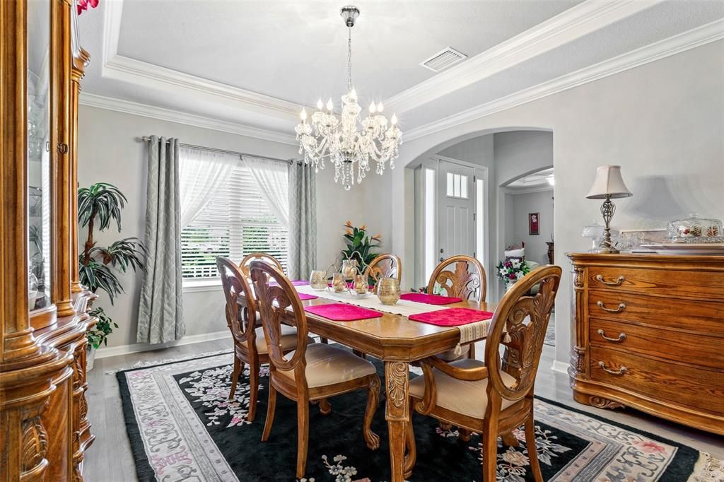 Your dining area sits front of the home with chandelier, vinyl flooring, and access to the kitchen.