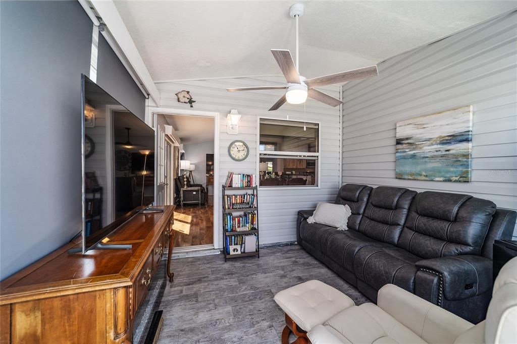 FRONT GLASS ENCLOSED LANAI WITH WOOD LOOK PORCELAIN FLOORING AND SUNSHADES.