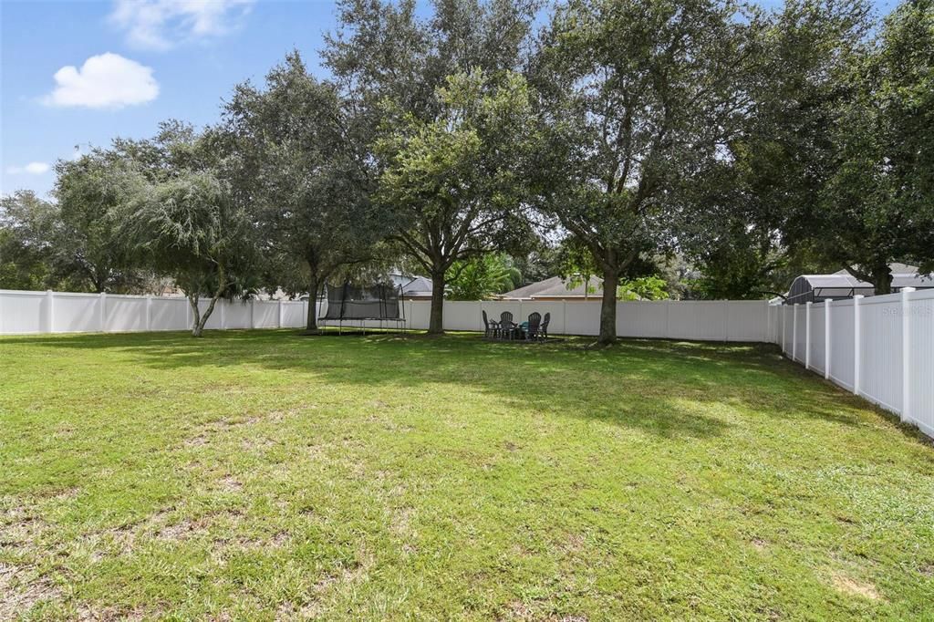 Huge fenced back yard with view of trampoline and fire pit. Both will convey with the home.