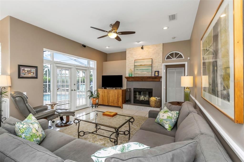 Comfortable family room complete with wood burning fireplace and French doors to the screen enclosed pool area.