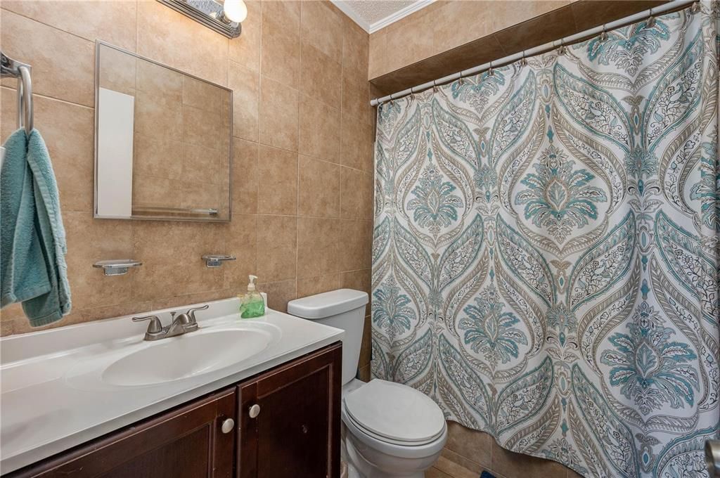 Second bathroom showing mirror, vanity, and shower-tub combo.