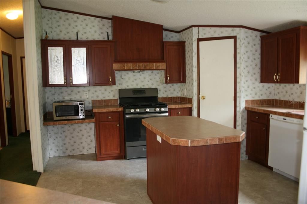 Kitchen with island,gas range, microwave,Refrigerator and a new hood fan (needs to be installed)