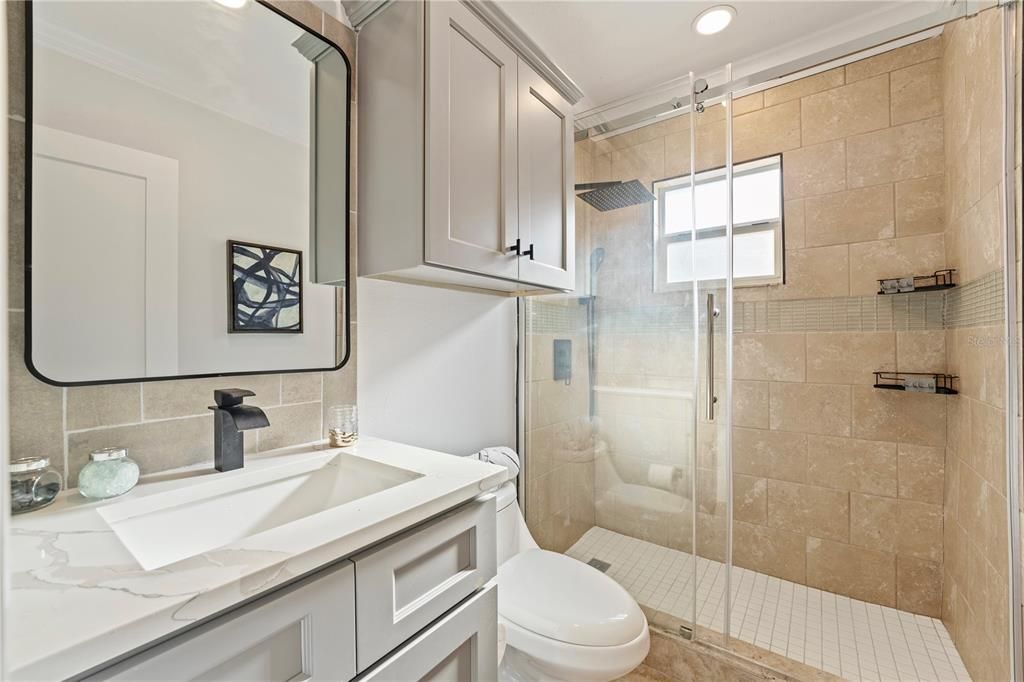 Bathroom #1. Situated between bedroom 1 & 2 off the main living area. A completely remodeled full bath with quartz counters and seamless glass multi-head shower.