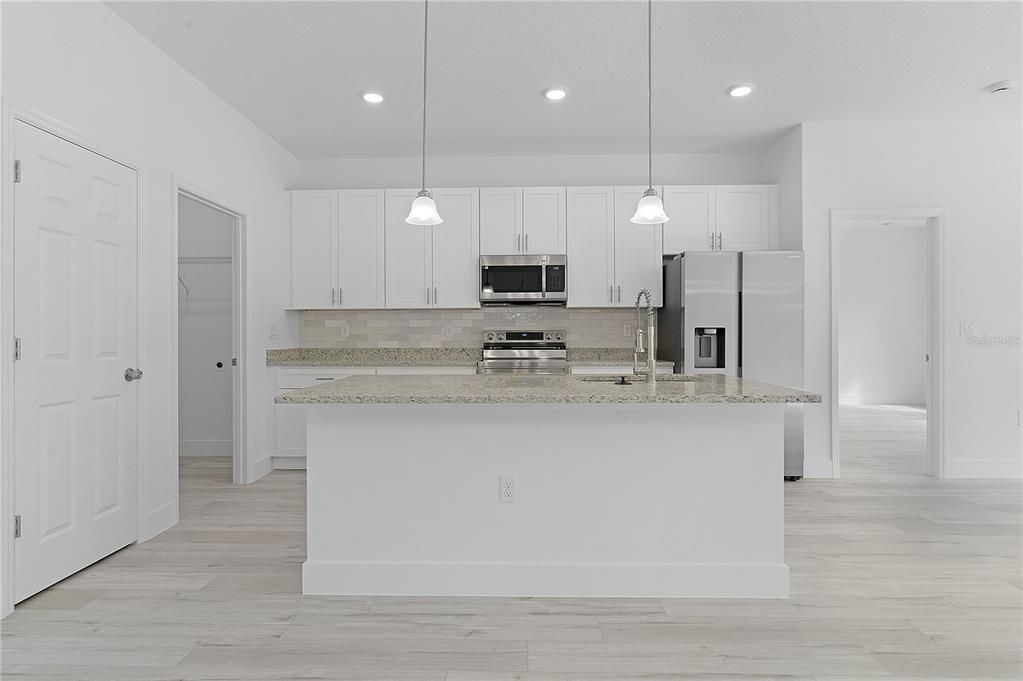 Laundry room is to the left of the kitchen, and primary suite is through the door to the right of the kitchen