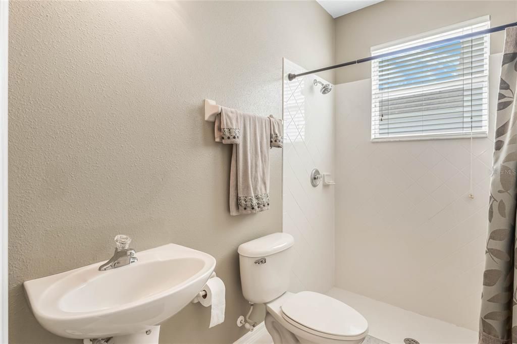 Guest bathroom with shower, pedestal sink and toilet.