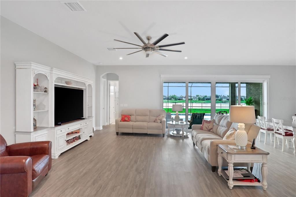 great room with luxury vinyl plank flooring and a view of the pool and lake through the pocket sliding doors