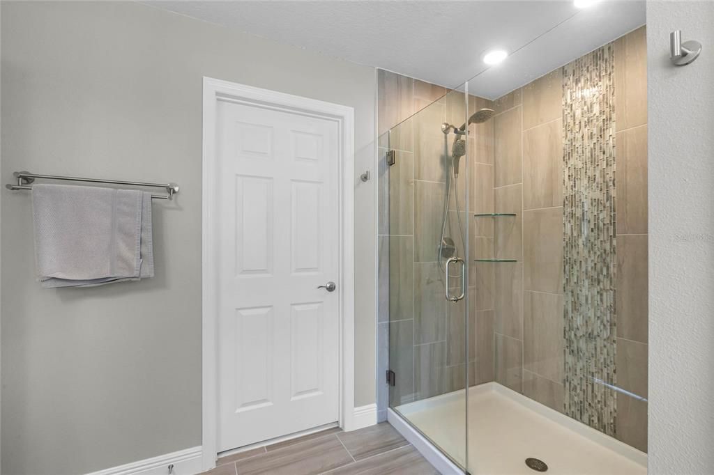 primary bath with enclosed shower, and large walk-in closet