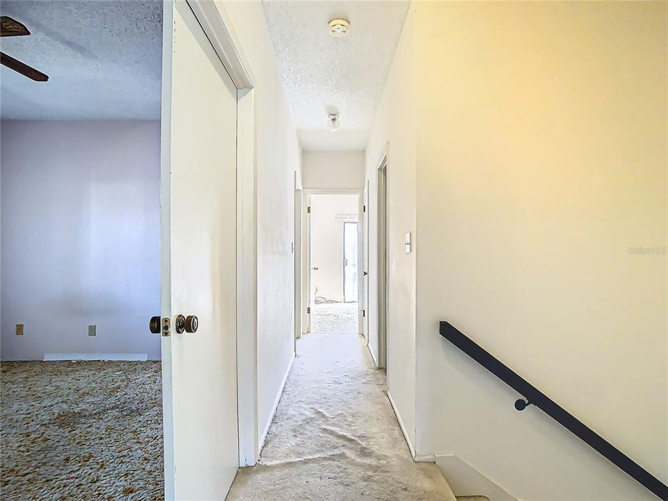 The hallway taking you from the primary suite to three bedrooms and a bathroom.