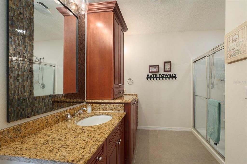 Ensuite primary bathroom with split vanity, extra cabinet, large shower, storage closet and private water closet