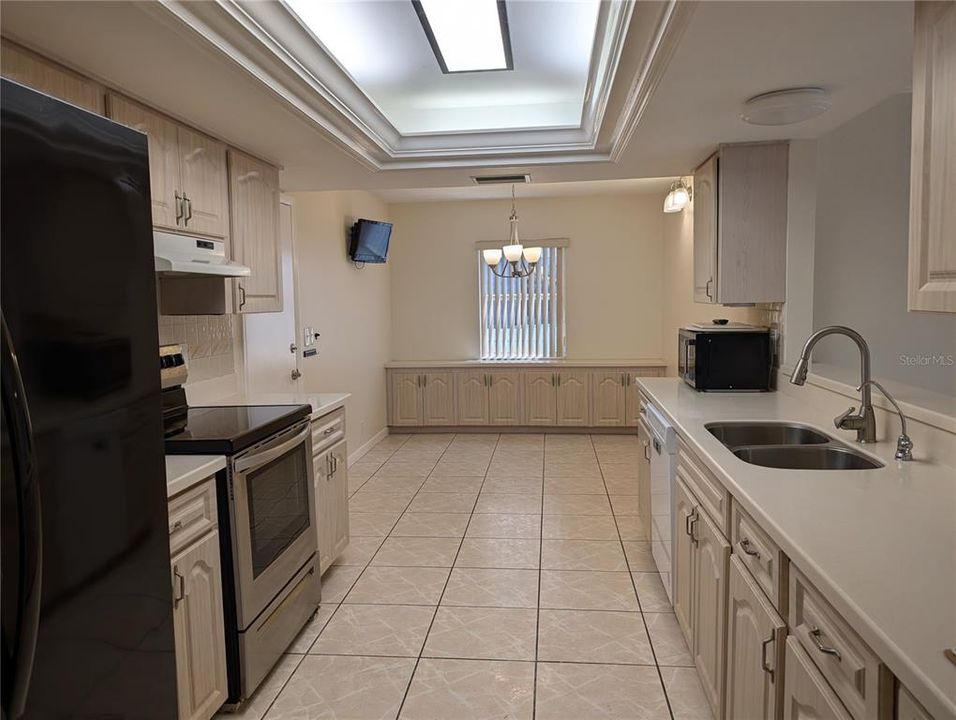 Eat in galley kitchen features Corian countertops, ample cabinetry, inset ceiling light and access to garage on left.