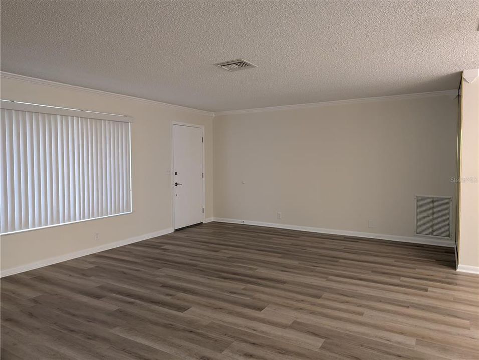 Living room feature laminate flooring, crown molding and a neutral decor just painted.