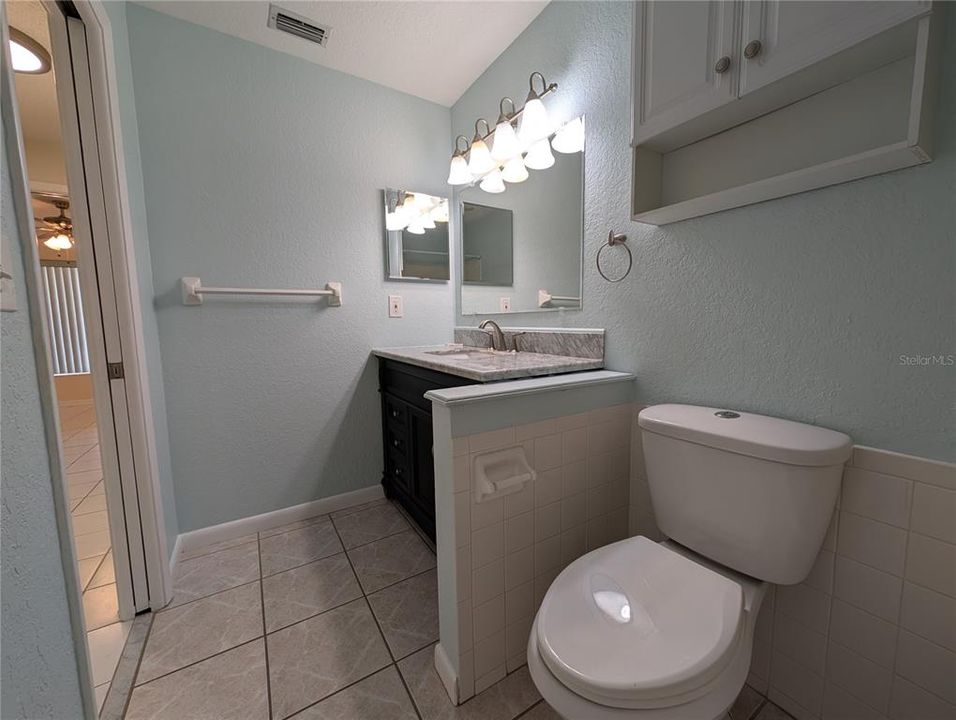 Updated guest bath features tile floor, custom vanity with marble sinktop, comfort height commode, toiletry cabinet and medicine chest. Pocket door is a space saver.