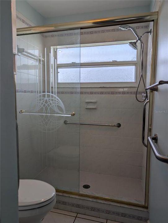 Stunning walk-in shower with decorative glass shower door. Window provides extra light and airflow.