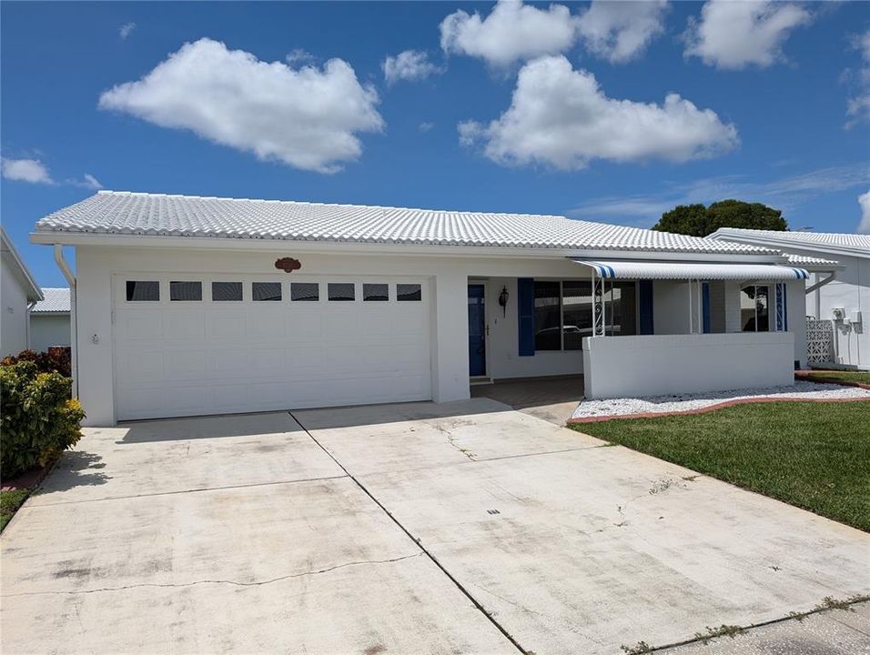 Exterior view of 2 car driveway and garage.  Other exterior features include tile roof, awning, gutters, downspouts, updated windows and cement landscape curbing.