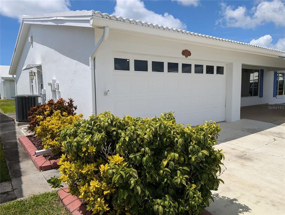 Exterior side view of cement block sidewalk from front to backyard, side garage door and Trane AC.