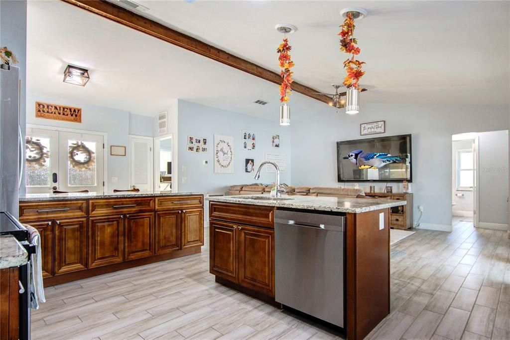 Open kitchen with vaulted ceiling, skylight, wood cabinets, granite countertops, and stainless steel appliances