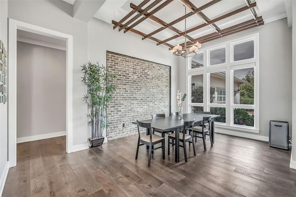 Formal Dining room with brick accent wall and floating beams