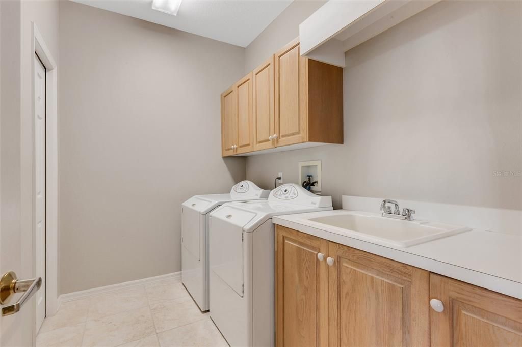 Inside laundry room with sink, cabinets, and storage closet