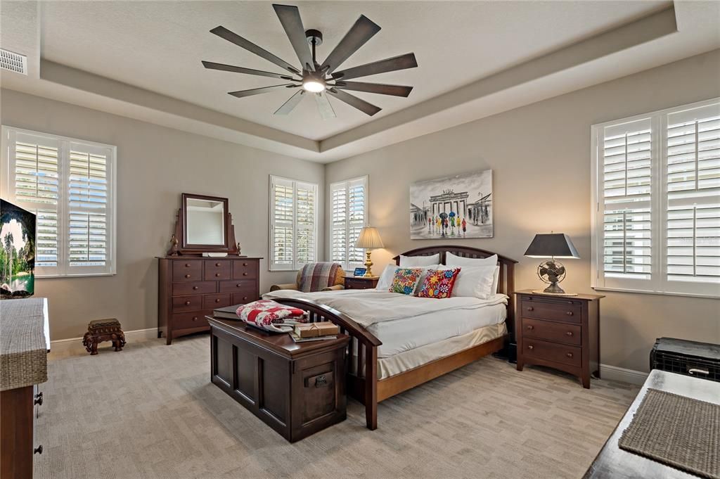 PRIMARY BEDROOM WITH TRAY CEILINGS AND NEW CEILING FAN