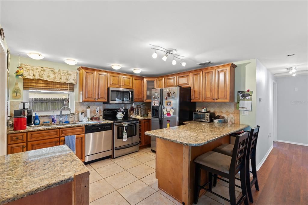 Renovated kitchen featuring stainless steel appliances, ample wood cabinetry, and breakfast bar.