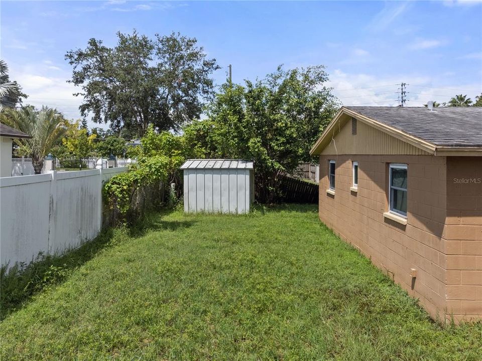 Fully fenced-in back yard featuring a shed for storage.