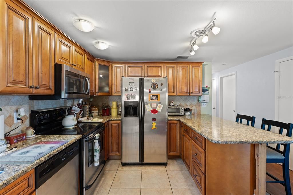 Renovated kitchen featuring stainless steel appliances, ample wood cabinetry, and breakfast bar.