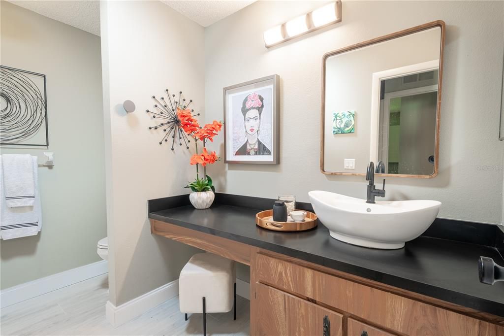 Bathroom 2 features a mirrored vanity with vessel sink, new counter top, neutral tone walls and wood laminate flooring.