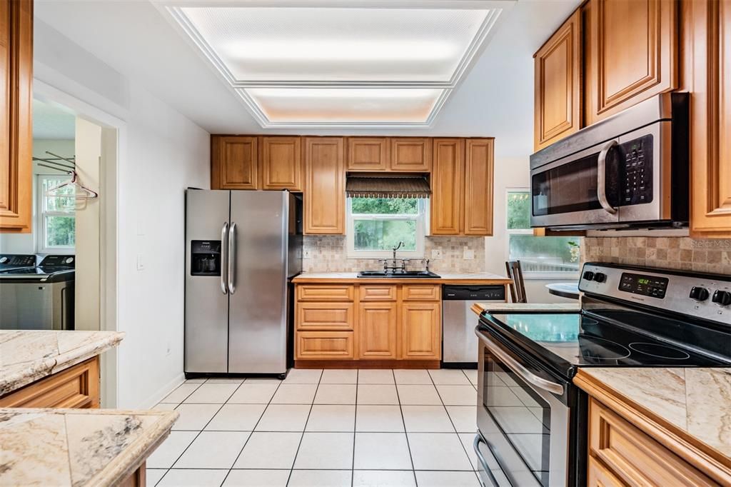 Open Kitchen with Stainless Steel Appliances, Tile countertops and tile flooring.