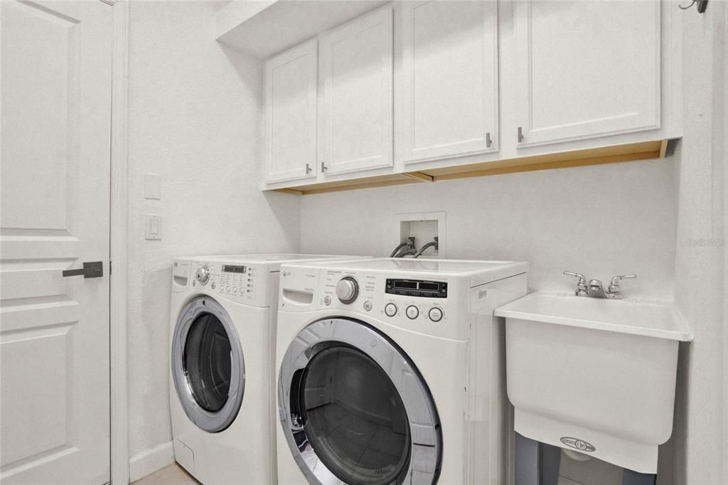 Conveniently located off the kitchen, the laundry room features cabinets for extra storage, a utility sink, and provides direct access to the 2-car garage.