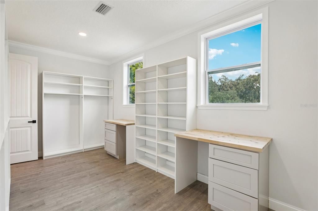 View of primary walk-in closet. Laundry baskets can easily tuck under the dual builtin cabinets. Rods will be added to the end cabinets.