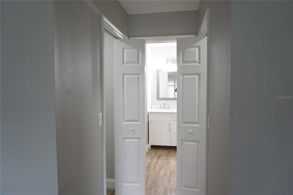 Primary bedroom hall into bathroom with walk-in closets on both sides