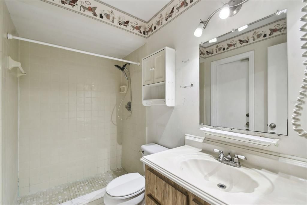 Primary bathroom adjoins owner's bedroom and offers a tiled walk-in shower and single door access to the screened lanai