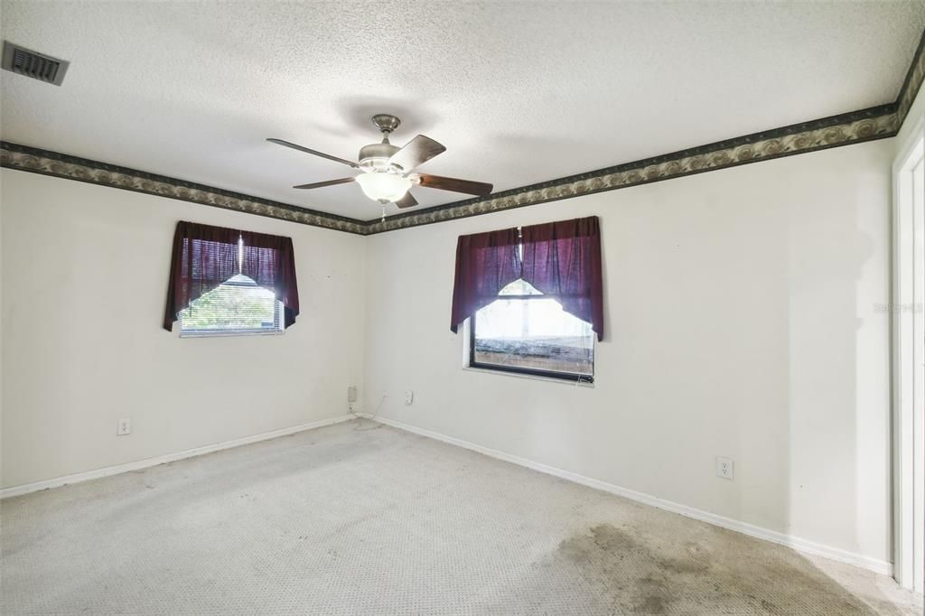 Primary bedroom faces the backyard with en-suite bathroom and screened patio access