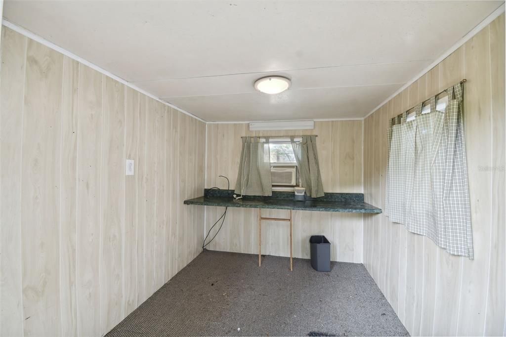 Backyard workshop/shed has a cozy craft room on the back side with a window unit AC, and finished walls and flooring. There's even cable t.v. connection inside.