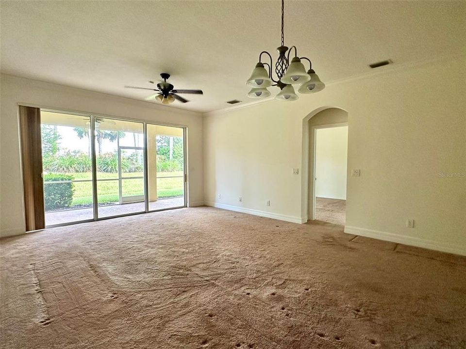 Spacious living room with triple sliders to extended screened lanai, primary bedroom on right